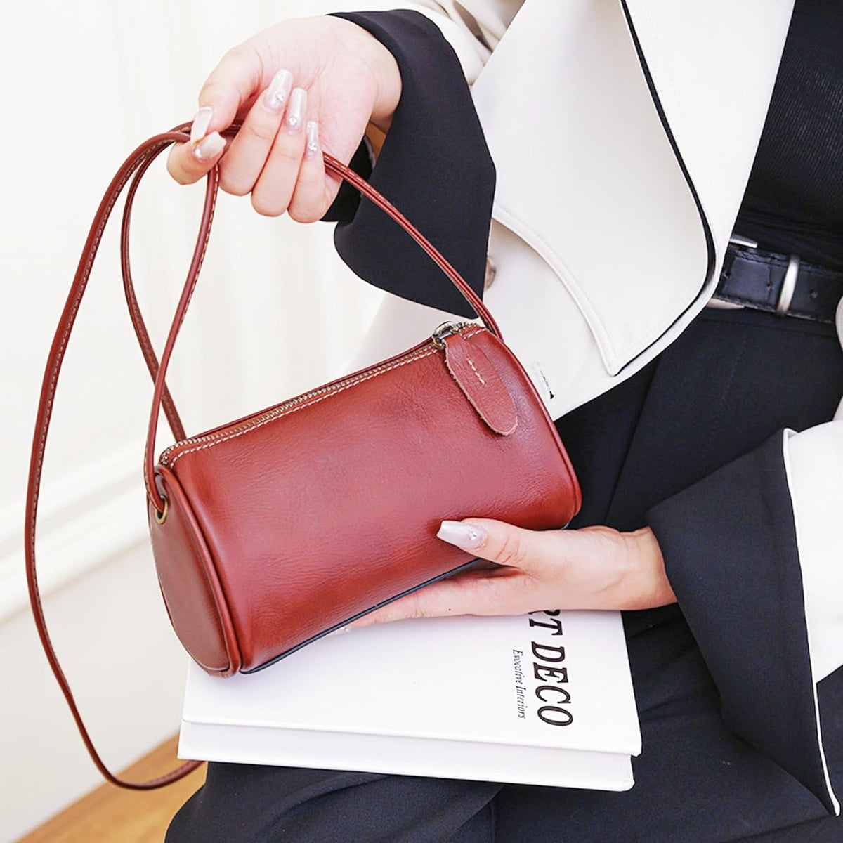 Coffee Leather Crossbody Bag carried by hand with a graceful shape and timeless leather style for daily occasions